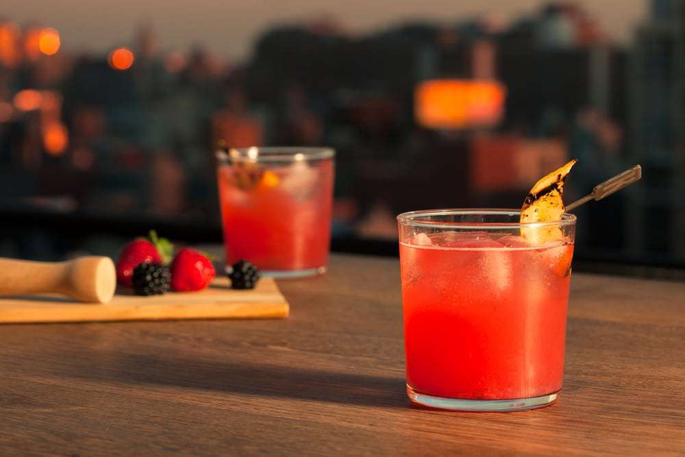 Berry fizz cocktail with panoramic New York City skyline backdrop - rooftop lifestyle beverage photography