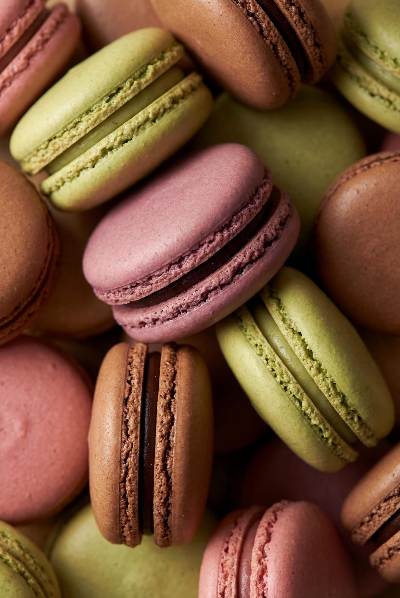 Pastel macarons in pink, green, and lavender arranged in a grid pattern