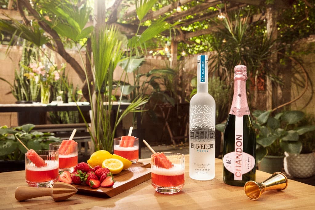 Belvedere Vodka and Chandon Garden Spritz bottles on a sun-drenched garden table with summer garnishes