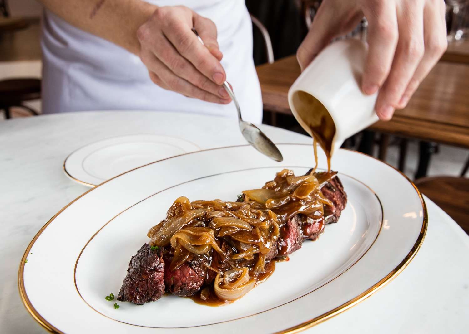 This skirt steak is being smothered in an onion sauce and served tableside at an NYC Restaurant.